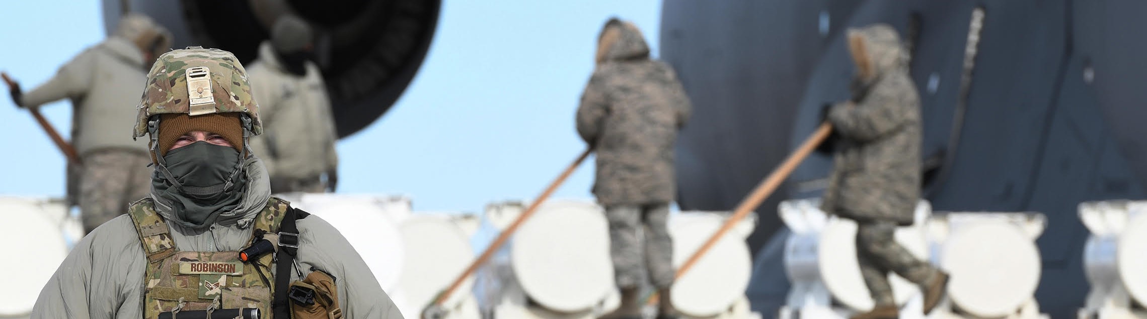 An image of an Airman with flak jacket and kevlar on standing outside.